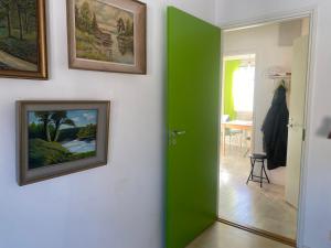 a green door in a room with paintings on the wall at Värikäs puutalokaksio 1-6 hlölle, ilm parkit in Oulu