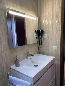 a bathroom with a white sink and a mirror at Casa da Vista- Eirinha in Furnas