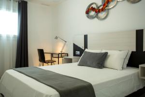 a bedroom with a large white bed and a chair at Apartamentos Aponiente in Conil de la Frontera