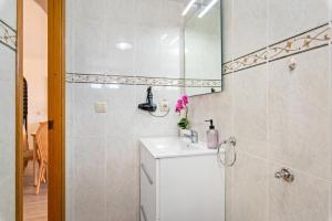 Baño blanco con lavabo y espejo en Apartamento Arenal 7 - PlusHolidays, en Calpe