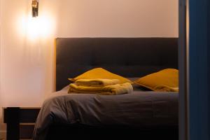 ein Schlafzimmer mit einem Bett mit gelben Kissen in der Unterkunft La Ferme de Bacchus in Hautvillers