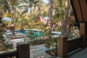 a resort with a swimming pool and palm trees at Selvática in Gili Islands