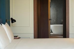 a bedroom with a bed and a bathroom with a tub at Nobu Hotel Sevilla in Seville