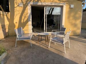 um grupo de cadeiras e uma mesa em frente a um edifício em Villa Premium 3 étoiles sur Terrain clos de 300 M2 em Bagnols-sur-Cèze