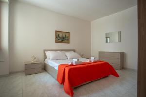 una camera da letto con un letto con una coperta rossa sopra di Residence Via Milano a Marina di Mancaversa