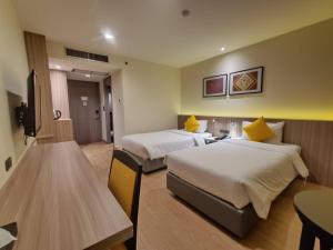 um quarto de hotel com duas camas e uma mesa em Le cassia Hotel em Khon Kaen