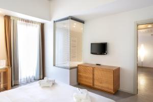 a bedroom with a tv and a dresser with two chairs at The Ziba Hotel & Spa in Peschiera del Garda