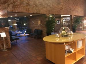 Bymose Hegn Hotel & Kursuscenter في Helsinge: لوبي مع طاولة وكراسي وجدار من الطوب