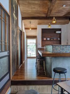 a kitchen with wooden floors and a bar with stools at 　Komori Village GH ～小森ヴィレッジ ゲストハウス～ 自然の中にある庭付平屋一棟貸 