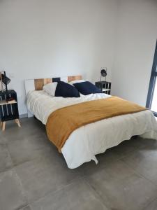 ein Schlafzimmer mit einem großen Bett mit weißer Bettwäsche und blauen Kissen in der Unterkunft Maisons T2 avec jardins privatifs - 10mn de la plage et 5mn du village - Casa di i trinelli in Vescovato