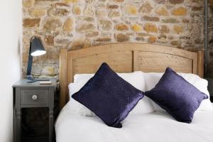 a bed with two purple pillows on top of it at Pen Dragon - 2 Bedroom Cottage - Pen-Clawdd in Gowerton