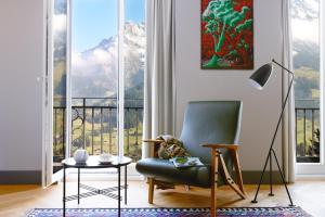a living room with a chair and a large window at Bellevue Parkhotel & Spa - Relais & Châteaux in Adelboden +67 photos