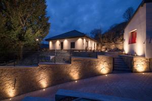 a house with lights in front of a stone wall at Szikla apartmanok Visegrád in Visegrád