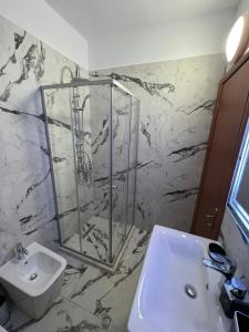 a bathroom with a sink and a glass shower at Sunlit Coast Apartment Durrës in Durrës