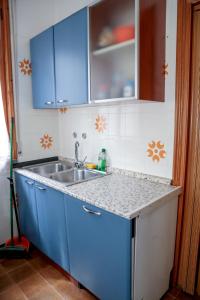 uma cozinha com armários azuis e um lavatório em Guest House Via Emilia 