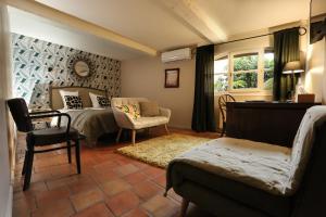 een slaapkamer met een bed, een stoel en een bank bij La Treille Muscate in Cliousclat