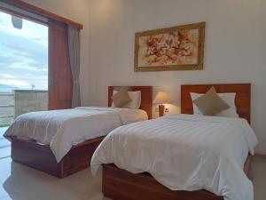 two beds in a hotel room with a window at D'TRANSIT in Nusa Penida