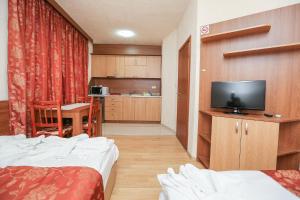 a hotel room with two beds and a flat screen tv at Къща за гости "ВАИС" in Sandanski