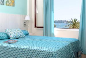una camera con un letto blu e una finestra di Apartamentos Sivella a Port de Pollença
