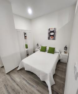 a white bedroom with a white bed with green pillows at Green Apartamentos Cartagena in Cartagena