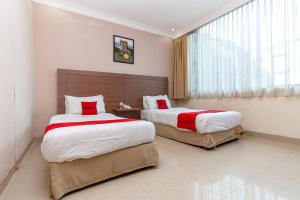 a hotel room with two beds and a window at RedDoorz Premium at Hotel Ratu Residence in Paalmerah