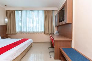 Habitación de hotel con cama, escritorio y TV. en RedDoorz Premium at Hotel Ratu Residence en Paalmerah