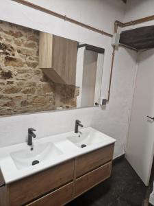 a bathroom with two sinks and a stone wall at Casa María Rosa in Baños de la Encina +12 photos