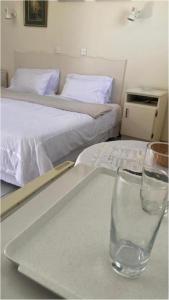 a table with a glass on a table with two beds at Neat standard room in guesthouse - 2088 in Bulawayo
