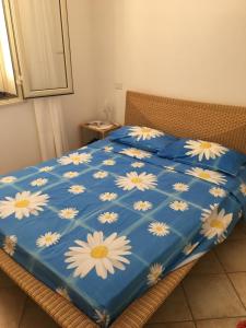 a blue comforter with white flowers on a bed at Attico sul Porto Vecchio - Lampedusa in Lampedusa
