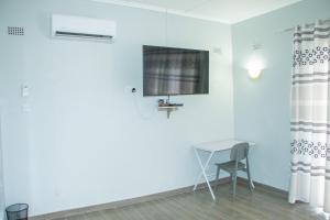 a room with a table and a television on a wall at Neat one bedroom in Morningside guesthouse - 2089 in Bulawayo