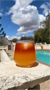 a glass of orange liquid sitting on a ledge next to a pool at Twin Room in Hillside - 2087 in Bulawayo