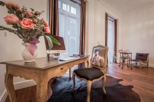 a room with a desk with a vase of flowers on it at Purple Dog Suites in León
