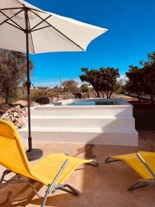 duas cadeiras amarelas e um guarda-sol ao lado de uma piscina em Paraíso a Dois em Estremoz em Estremoz
