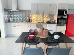 uma cozinha com uma mesa preta e cadeiras e um frigorífico vermelho em Villa Premium 3 étoiles sur Terrain clos de 300 M2 em Bagnols-sur-Cèze
