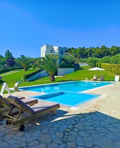 una piscina con un banco y una mesa en Possidi Hiliadou Boutique Resort, en Possidi