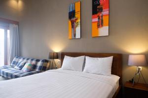 ein Schlafzimmer mit einem Bett und einem Stuhl sowie Gemälden an der Wand in der Unterkunft The Lavana Valvilla in Timuran