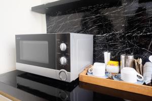 eine Mikrowelle mit Tassen auf einer Theke in der Unterkunft The Lavana Valvilla in Timuran