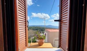 una ventana abierta con un jarrón sobre una mesa en un balcón en Seva Monolithos house en Monólithos