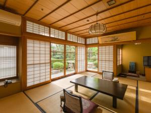 Hagi No Yado Tomoe في هاجي: غرفة مع طاولة وكراسي ونوافذ