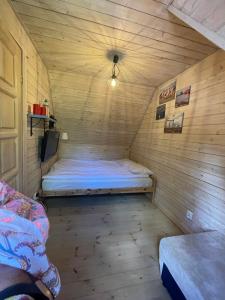 a small room with a bed in a wooden house at Zagroda Dębki in Dębki