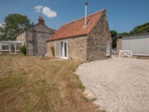 a small stone house with a gravel driveway at Little Rigg Cottage in Pickering