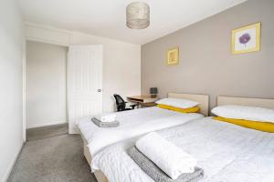two beds in a bedroom with a desk and a table at Stevenage Contractors x8 New 3 bedroom House Free Wifi, Parking, Towels all inclusive & Large Garden in Stevenage