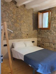 1 dormitorio con cama y pared de piedra en Les Cases del Moliner en Corbíns