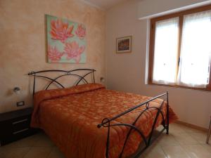 1 dormitorio con cama con sábanas de color naranja y ventana en Guest house Il Giardino in Città, en La Spezia