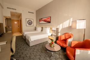 Peony Hotel في دبي: غرفه فندقيه بسرير واريكه وكراسي