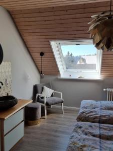 ein Schlafzimmer mit einem Fenster und einem Stuhl in der Unterkunft Chickenhill Blackforest, Ferienwohnung Großhans in Bad Wildbad