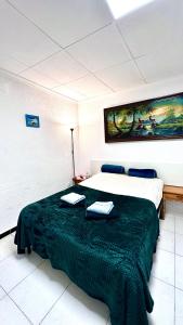 a bedroom with a large bed with a green blanket at Las habitaciones de Svetlana in Alicante