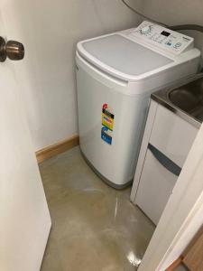 a white trash can in the corner of a kitchen at Joyful Esplanade City Stay in Darwin