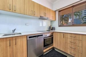 a kitchen with wooden cabinets and a stainless steel dishwasher at Joyful Esplanade City Stay in Darwin