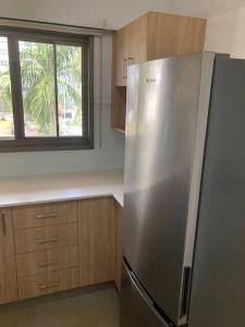 a stainless steel refrigerator in a kitchen with a window at Joyful Esplanade City Stay in Darwin